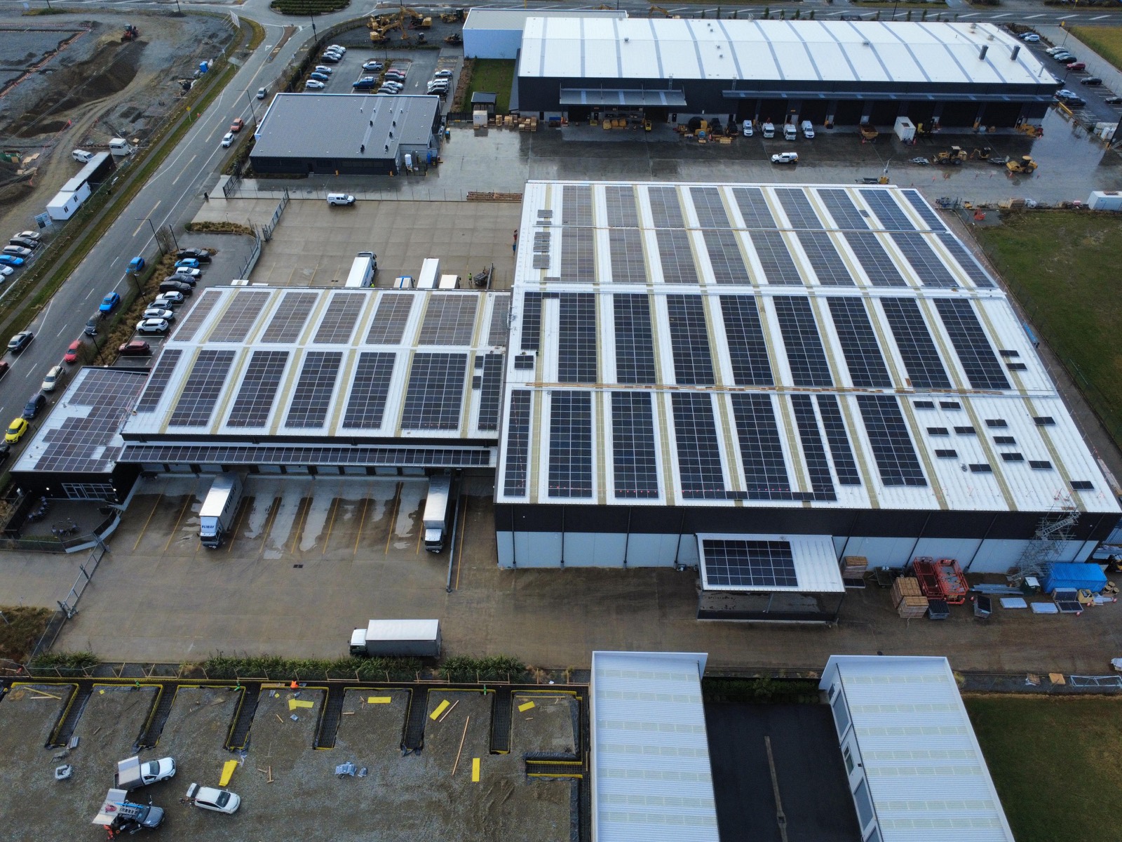 Aerial view of a large logistics hub with solar panels across its warehouse roofs and loading docks