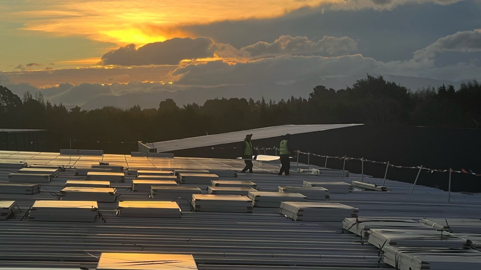 Generations Energy installers walking a commercial roof at sunset during a panel install